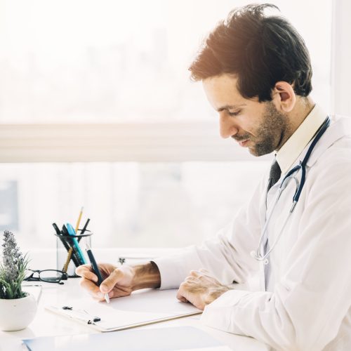 side-view-young-male-doctor-writing-clipboard-clinic